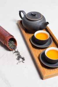 Tea pot & two filled cups of tea on wooden tray