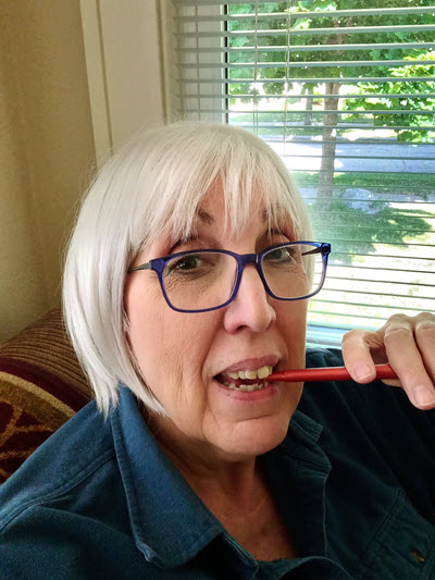 JA Jablonski. Caucasian Middle-aged person with white bob hairstyle wearing blue eyeglasses.